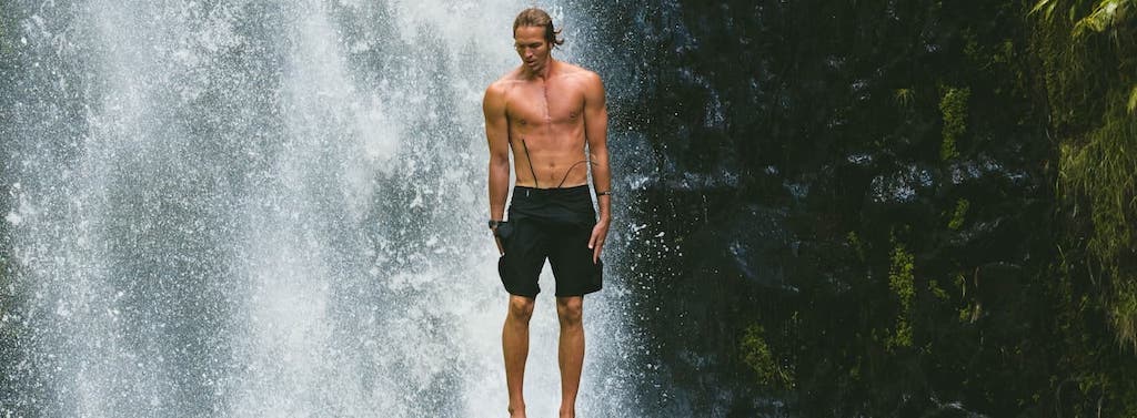 guy jumping in front of a water fall