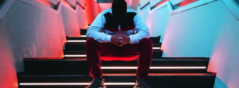 guy sitting in a neon lit stairway