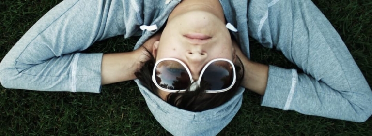 Young guy with sun glasses relaxing in the grass