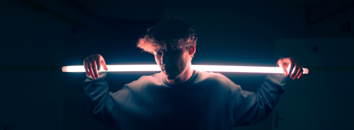 young guy back lit holding flourescent tube